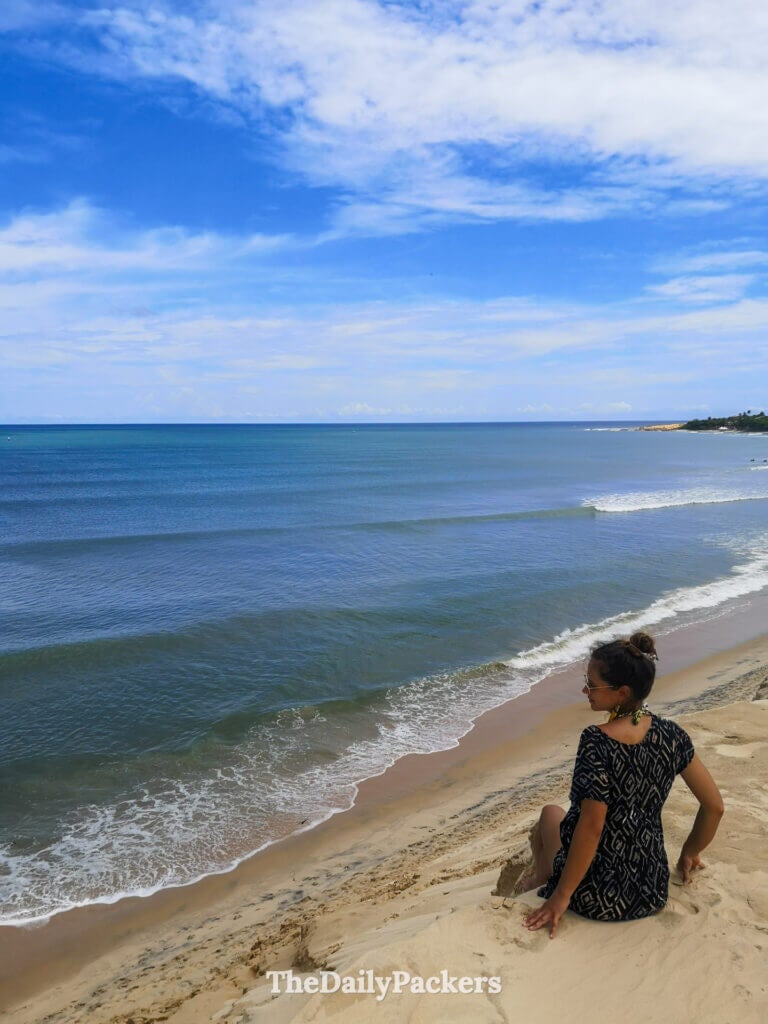 View from the top of Jericoacoara sand dunes, with sweeping ocean views, coastal village in the distance, and dramatic cloud formations