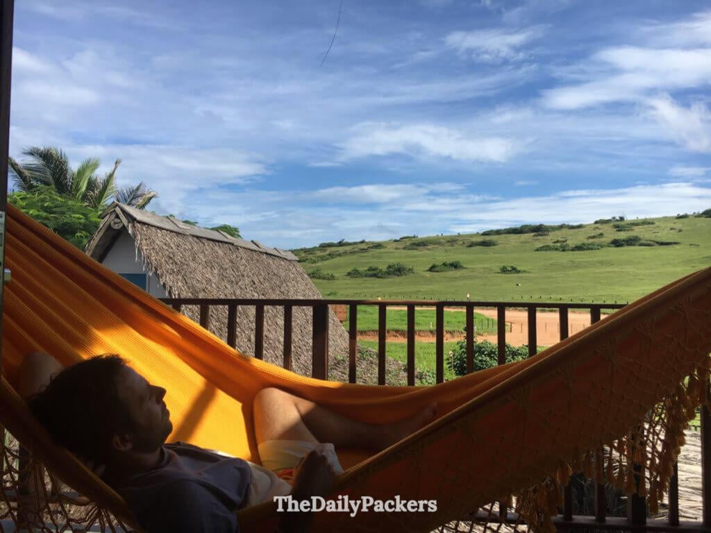 Traveler relaxing in a hammock on a balcony with countryside views near Jericoacoara, Ceará, surrounded by green hills and rural scenery