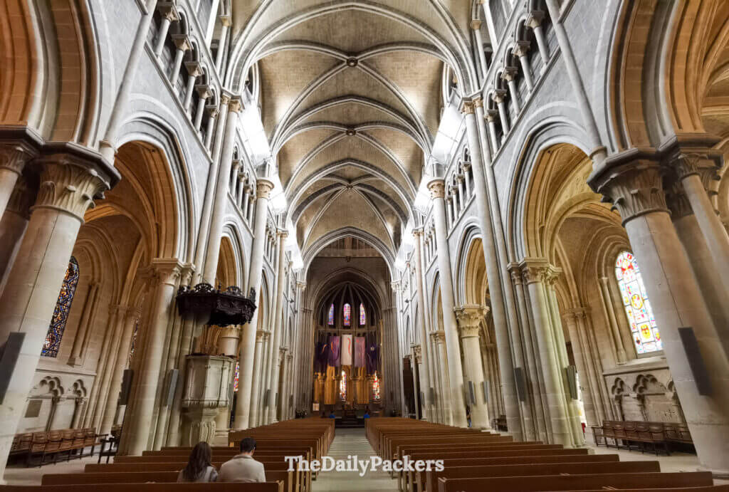 Interior of Lausanne Cathedral showing gothic arches, nave, stained glass and wooden pews