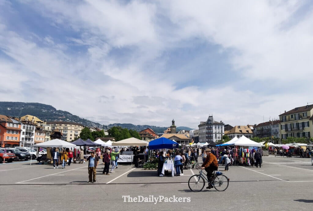 Vevey market square with local stalls, people shopping and mountains in the background