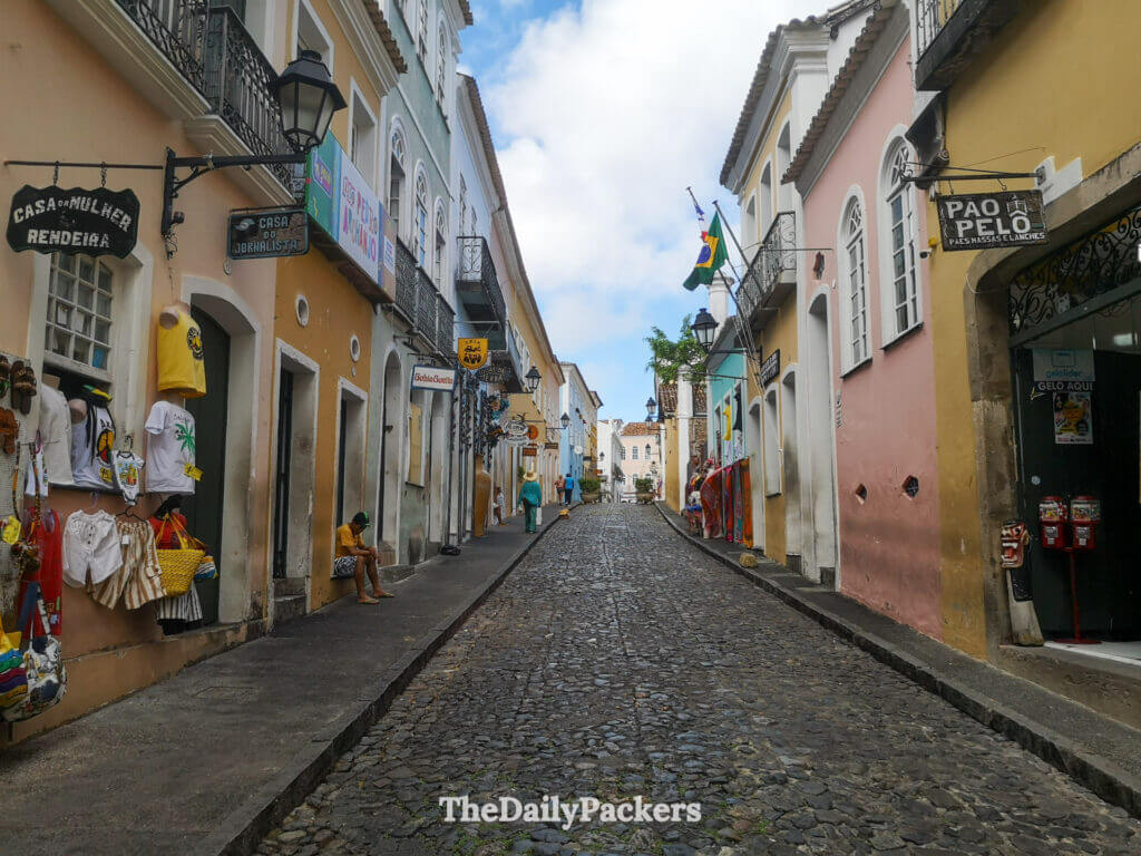 Colorful street in Salvador’s old town with souvenir shops, colonial houses, and a Brazilian flag hanging above the cobblestones