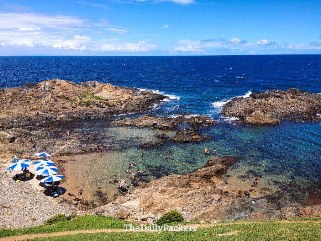 Natural rock pools at Farol da Barra beach in Salvador with people swimming in clear water beside the Atlantic Ocea