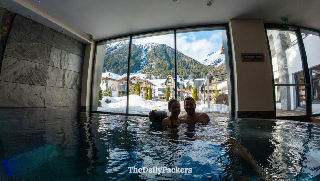 Indoor spa pool with mountain village and snowy Alps visible through large windows