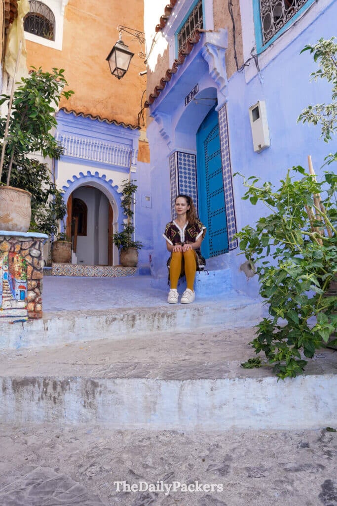 Traveler sitting in a blue alley doorway in Chefchaouen, the blue city of Morocco