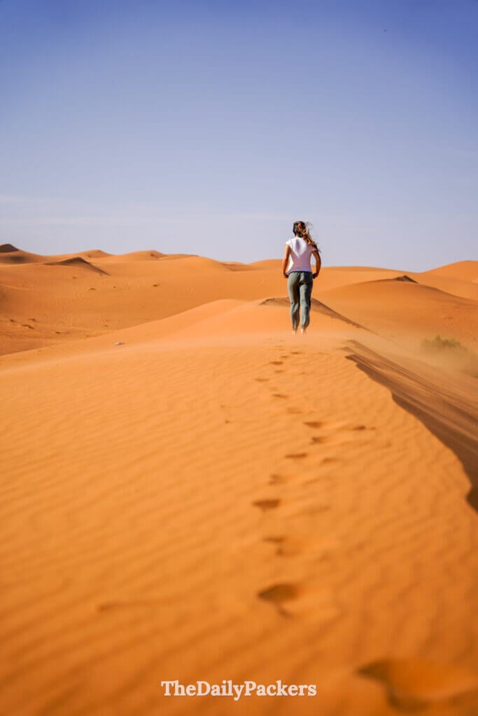 Woman walking on sand dunes in the Sahara Desert near Merzouga, Morocco