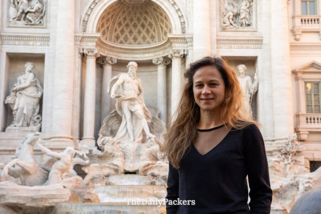 Woman standing in front of the Trevi Fountain with baroque sculptures in Rome