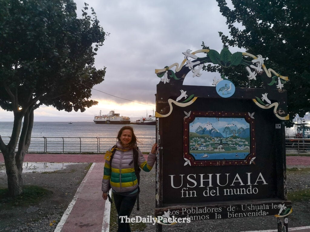 Traveler at Ushuaia fin del mundo sign on waterfront promenade