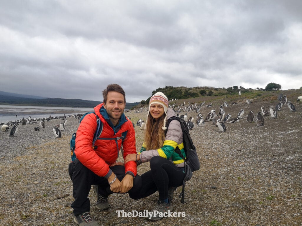 Couple with Magellanic penguins on Martillo Island, Beagle Channel