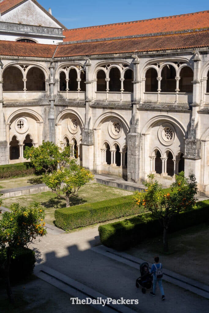 Un visiteur se promène dans les couloirs en pierre baignés de lumière du monastère d'Alcobaça.