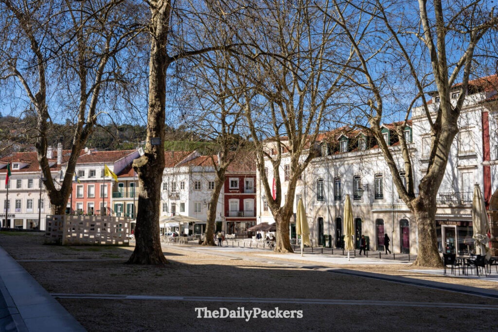 Place ensoleillée d'Alcobaça, avec ses bâtiments historiques et ses arbres dénudés, près du monastère.