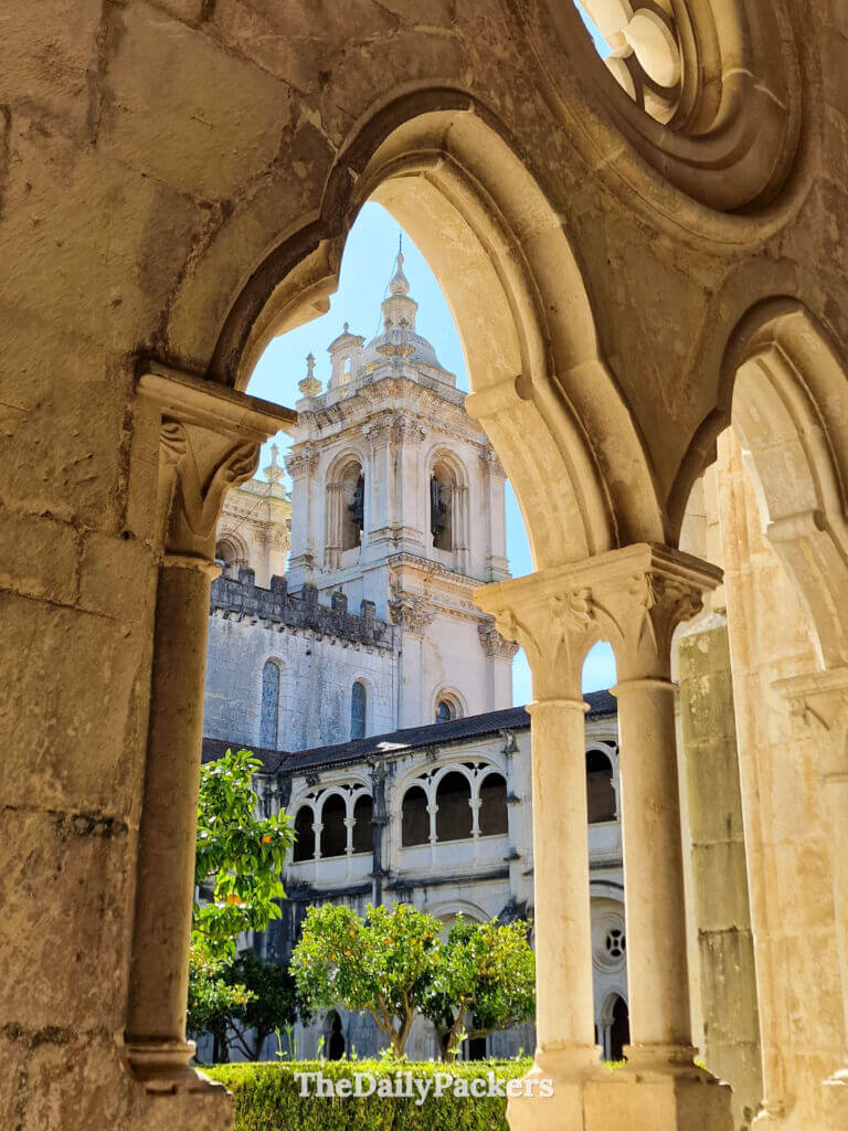 Vue du clocher d'un monastère, encadré par les arcades en pierre du Cloître du Silence.