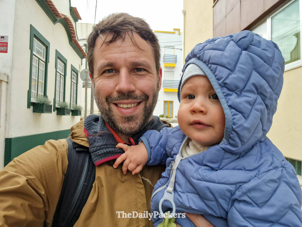 Un homme souriant prenant un selfie devant le canal emblématique et les bâtiments colorés d'Aveiro.