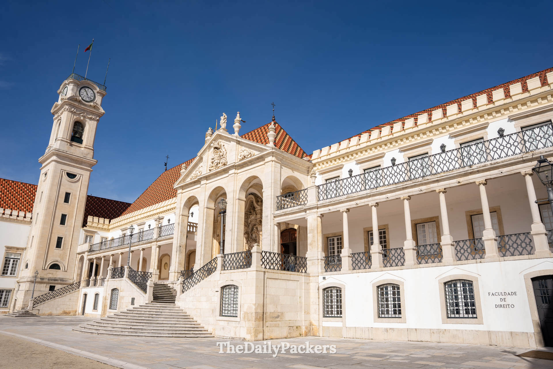 Le Palais royal et l’emblématique tour de l’horloge de l’Université de Coimbra sous un ciel bleu limpide.