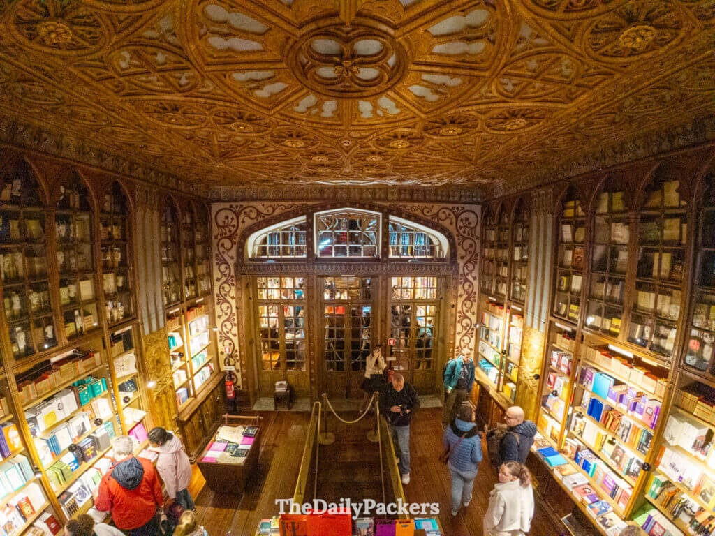Intricate carved wooden ceiling and expansive bookshelves inside the historic Livraria Lello.