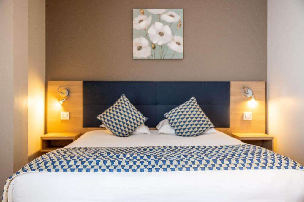 Modern and bright bedroom at the Adonis Hotel Le Bastia, showing a comfortable stay for a trip to Northern Corsica.