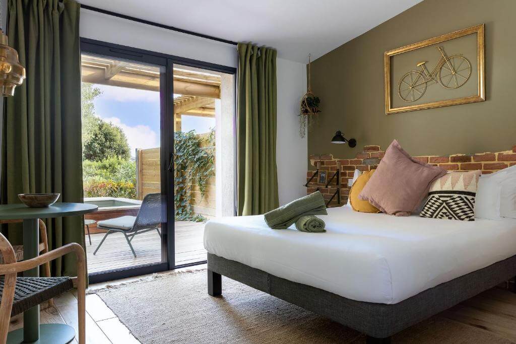 Modern and bright hotel room at Residence Casarina in Bonifacio featuring a large double bed, wooden accents, and a private terrace.