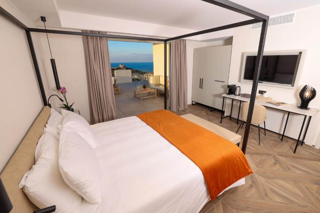 Luxury canopy bed at Hotel Maria Die in Calvi, opening onto a private terrace with Mediterranean views.