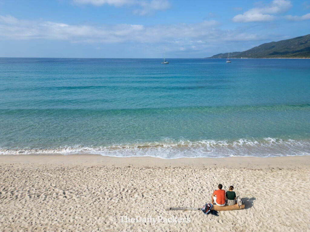 People relaxing on the sandy shores of Cupabia Beach, looking out at the crystal-clear water.