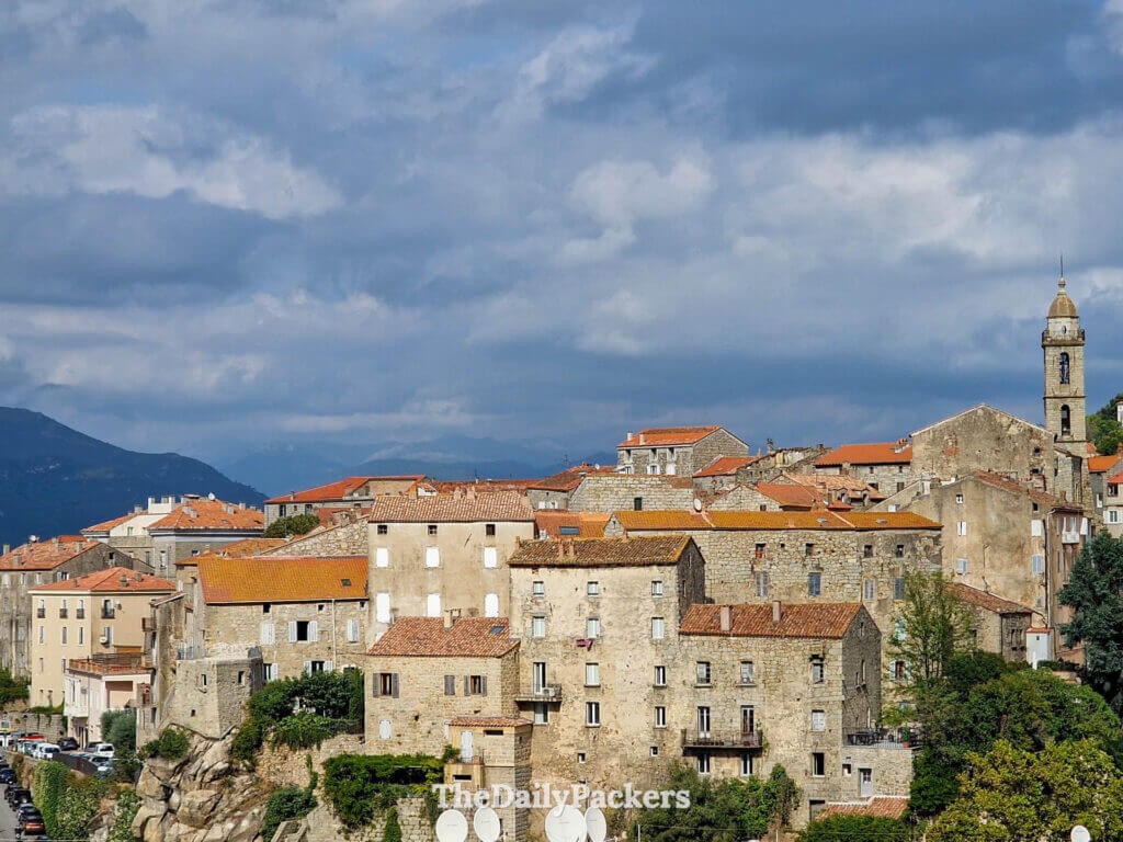 The picturesque stone buildings of Sartène climbing up the hillside under a blue sky.