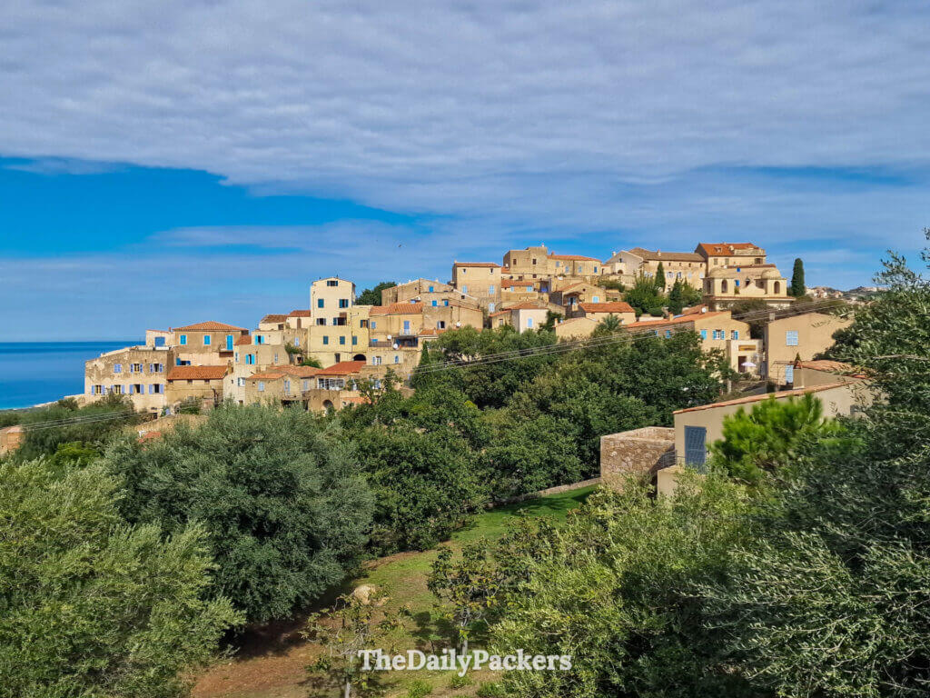 The picturesque stone houses of Pigna village clustered on a green hillside overlooking the valley.