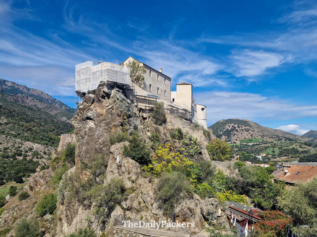 Panoramic view of the historic Citadel of Corte perched on a steep rocky hill.