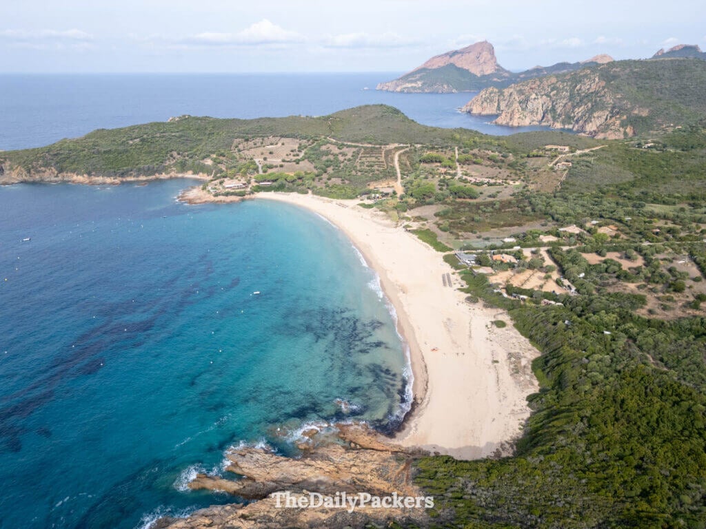 Aerial drone view of the wide sandy crescent at Arone Beach meeting clear turquoise water.