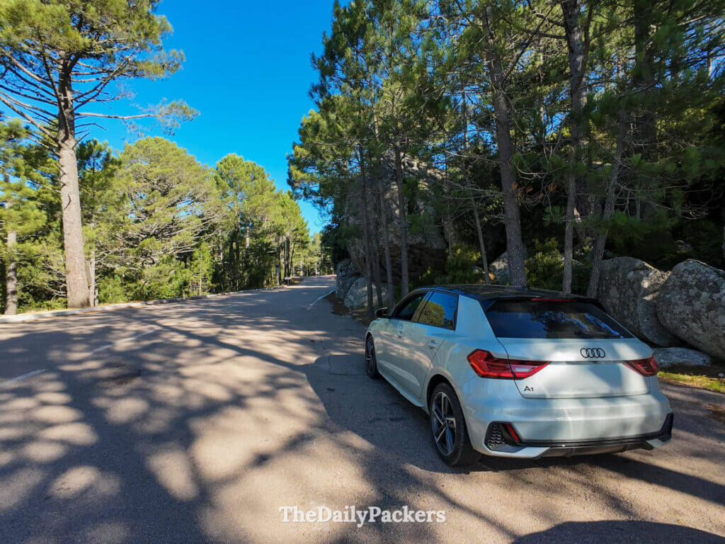 A grey Audi A1 rental car parked along a scenic mountain road in Corsica.