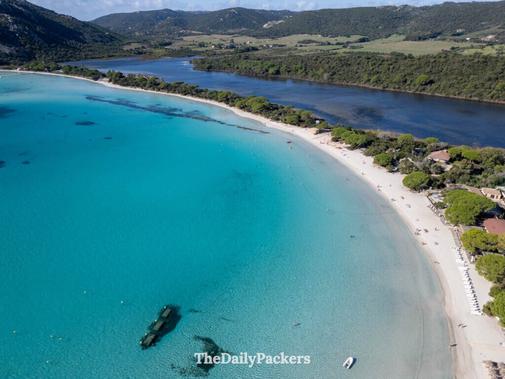Aerial view of the curved white sand shoreline and clear sea at Santa Giulia Beach, Corsica.