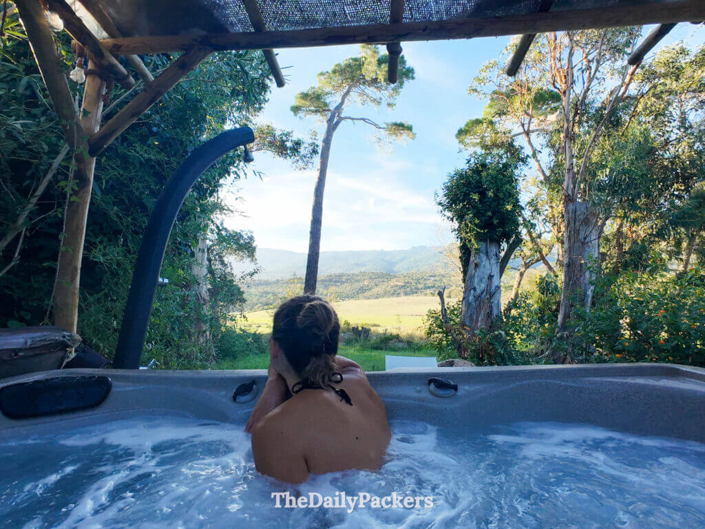 An outdoor jacuzzi hot tub on a wooden terrace surrounded by trees at U Barraconu guesthouse.