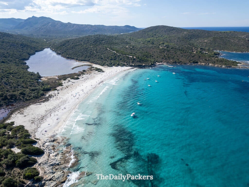 Vue aérienne par drone de petits bateaux ancrés dans les eaux turquoise vibrantes au large de la plage du Lotu.