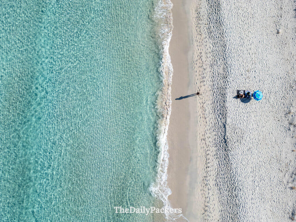 Aerial drone shot of a woman near the clear water of Saleccia beach in Corsica