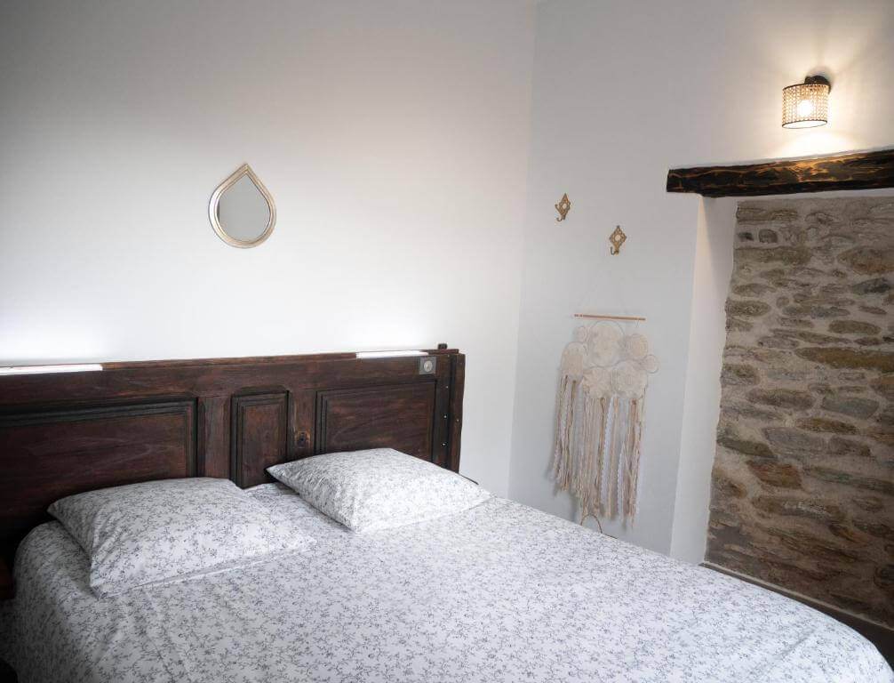 Rustic hotel room with dark wood and exposed stone at Hotel Mulinu Biancu in Saint Florent.