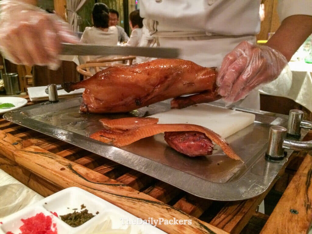 Un chef découpe un canard laqué de Pékin entier à table dans un restaurant traditionnel de Pékin