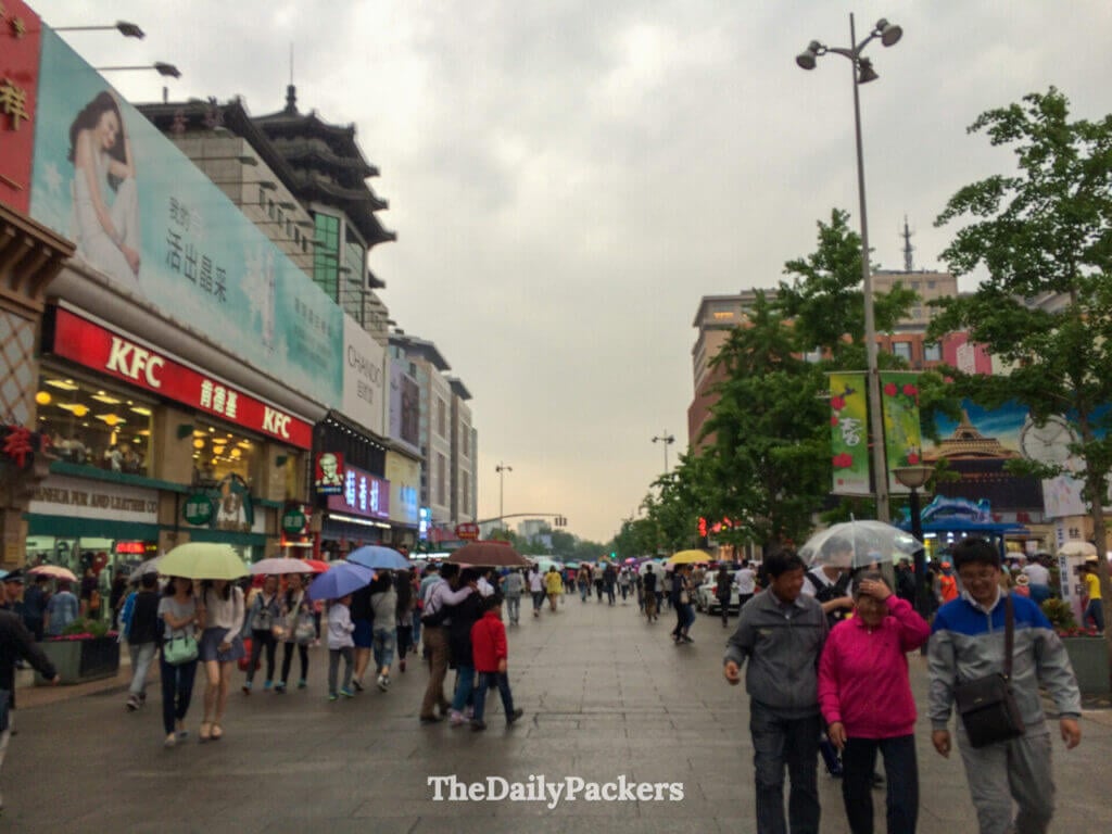Des passants avec des parapluies sur la rue commerçante piétonne de Wangfujing, sous la pluie, dans le centre-ville de Pékin