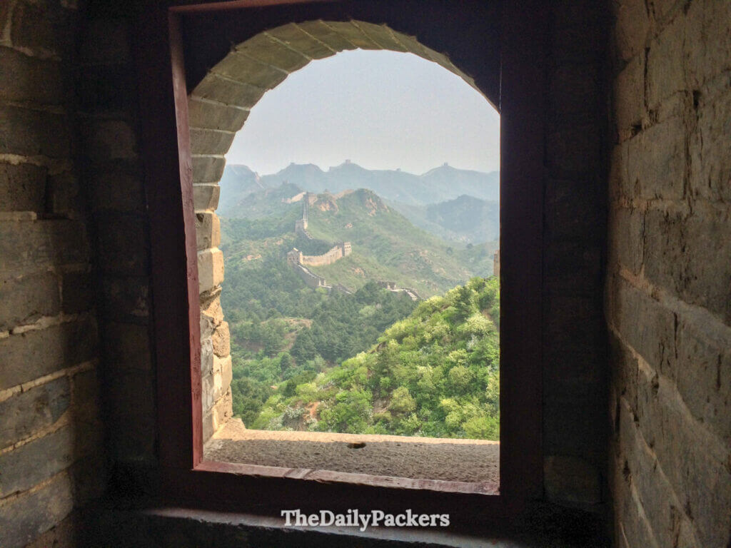 Arched watchtower window framing Jinshanling Great Wall snaking over green hills