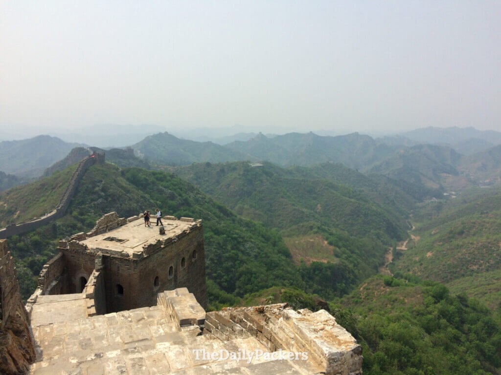 Touristes au sommet d’une tour de guet en ruines à Jinshanling, avec vues panoramiques sur la Grande Muraille et les vallées du Hebei