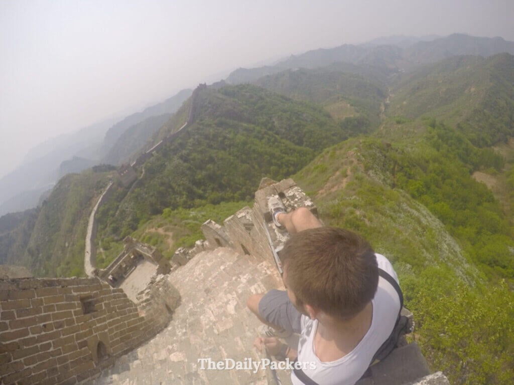 Traveler pointing over the crumbling wild section of Jinshanling Great Wall, Hebei, China