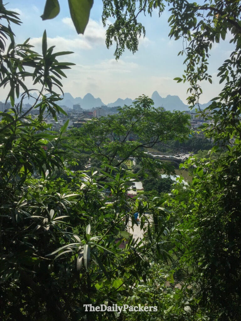 Distant karst peaks frame Guilin city and river through Xiangshan's greenery.