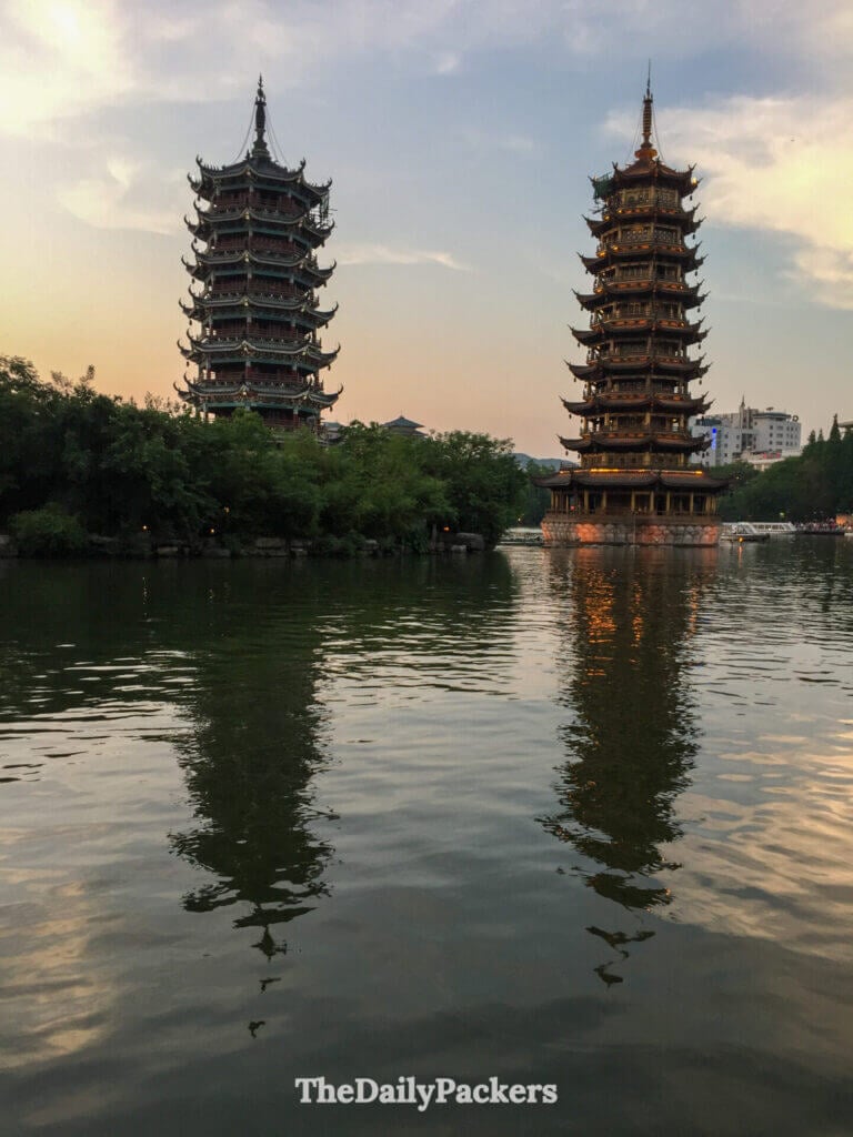 Sun and Moon Pagodas glowing at twilight, reflected in Shan Hu Lake, Guilin.
