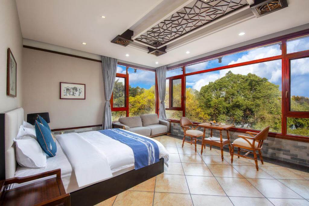 Bright hotel room with floor-to-ceiling windows overlooking Guilin's greenery.