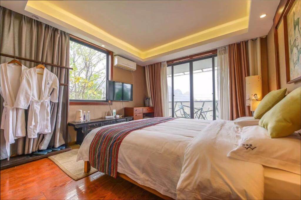 Cozy Guilin hotel room with balcony opening to karst peak scenery.