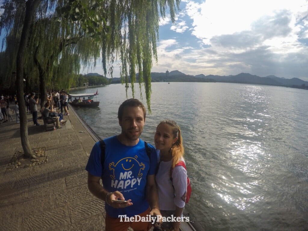 Couple posant au bord du lac de l’Ouest avec la pagode Leifeng et les montagnes en arrière-plan, Hangzhou