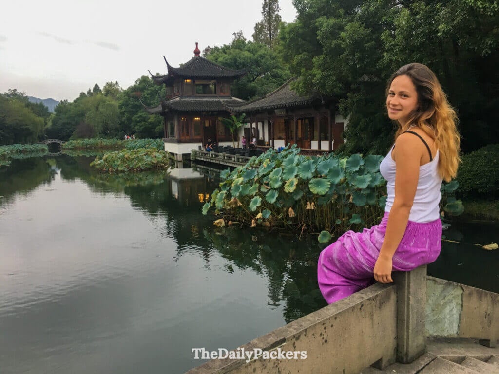Femme à côté d’un étang de lotus et d’un pavillon traditionnel aux Trois Bassins reflétant la Lune, Hangzhou