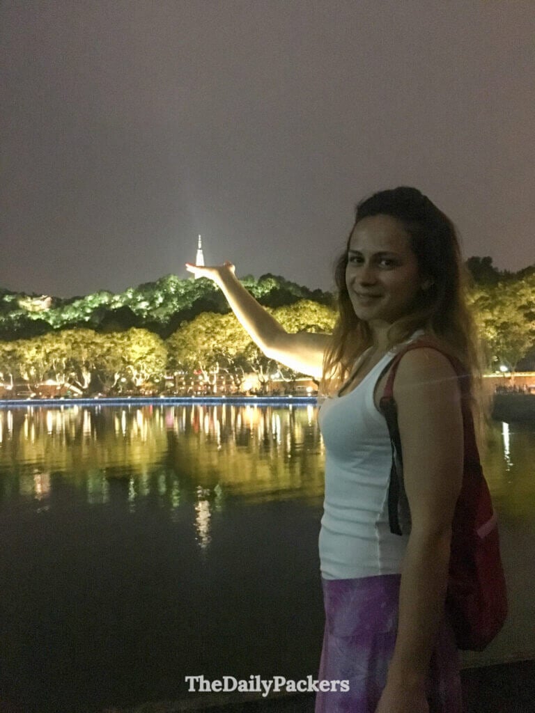 Femme pointant la pagode Baochu illuminée dominant le lac de l’Ouest la nuit, Hangzhou