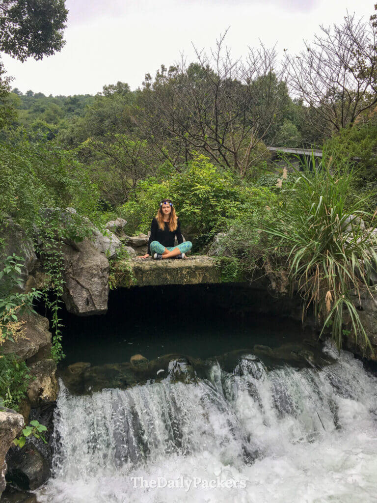 Femme méditant sur des rochers au-dessus d’une cascade aux 18 ruisseaux de Jiuxi, Hangzhou