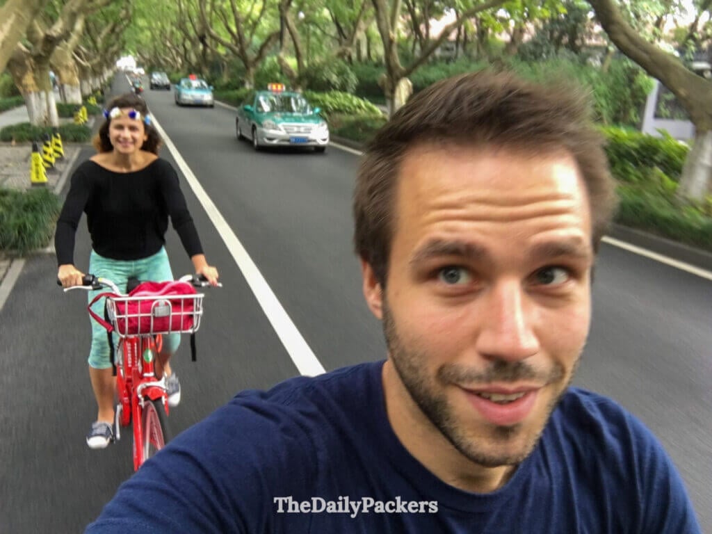 Couple roulant à vélo de location sur une route bordée d’arbres autour du lac de l’Ouest, Hangzhou