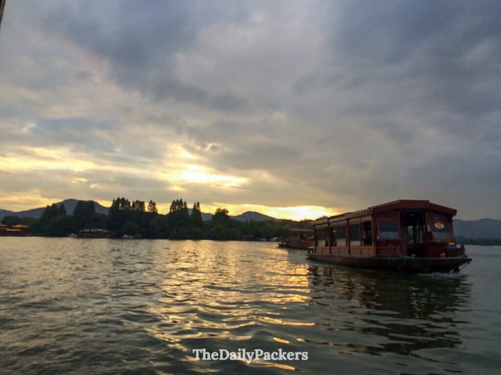 Bateau de visite traditionnel en bois naviguant au coucher du soleil sur le lac de l’Ouest aux Trois Bassins reflétant la Lune, Hangzhou