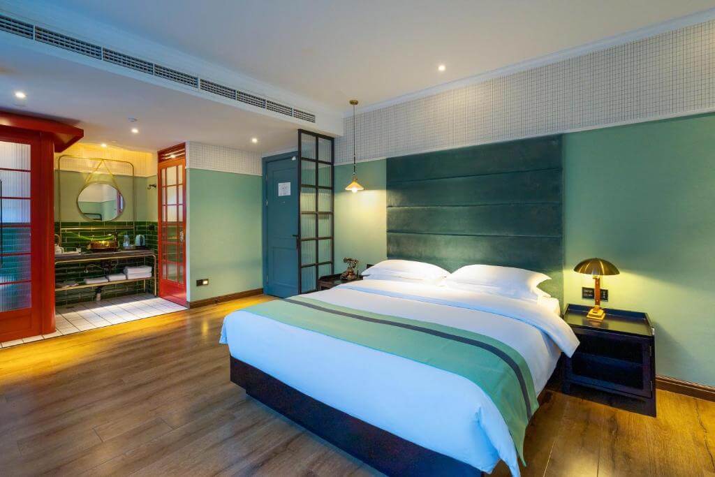 Chambre boutique élégante avec tête de lit bleu canard et salle de bain attenante à l’hôtel Lanshe, Hangzhou