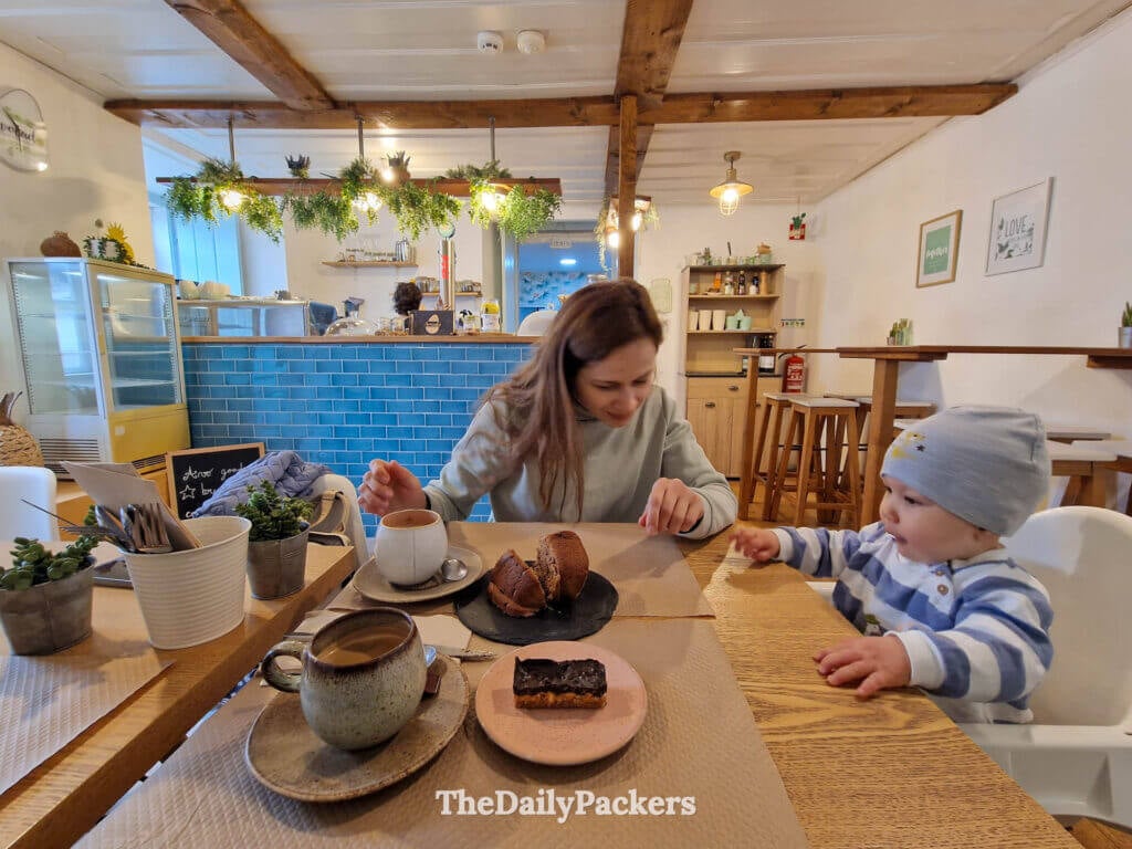 A woman and baby enjoy coffee and pastries inside a cozy café in Obidos, Portugal.
