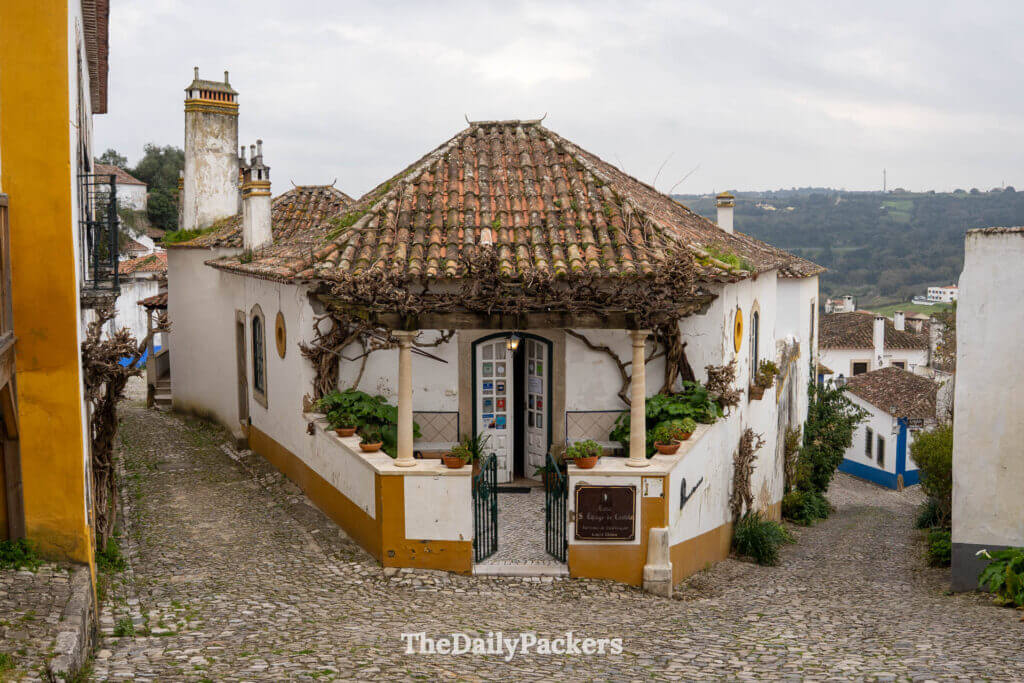 A charming white and yellow house situated at a fork on a cobblestone street in Obidos.